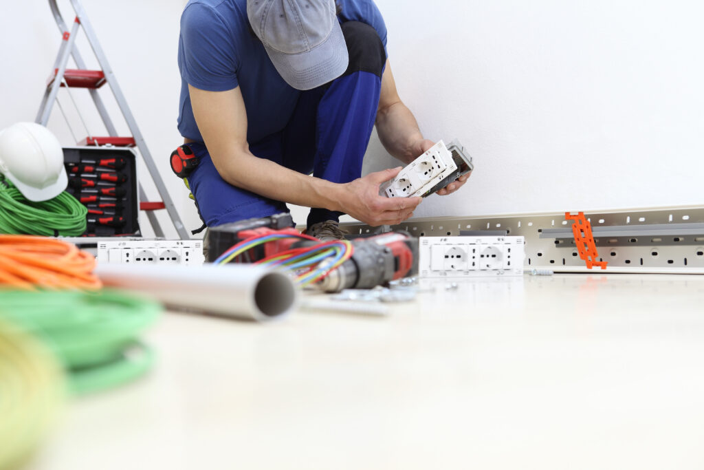 Électricien certifié avec habilitation électrique installant des prises électriques, respectant les normes de sécurité et de formation réglementaire